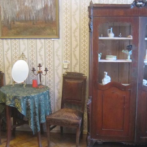 Книжный шкаф с коллекцией посуды, шахматный столик и стулья из музейной коллекции.
